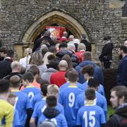 Harry Parker is carried into St Mary's Church of England by his father and brothers while his loved ones follow behind - many of which wearing bright colours and football shirts